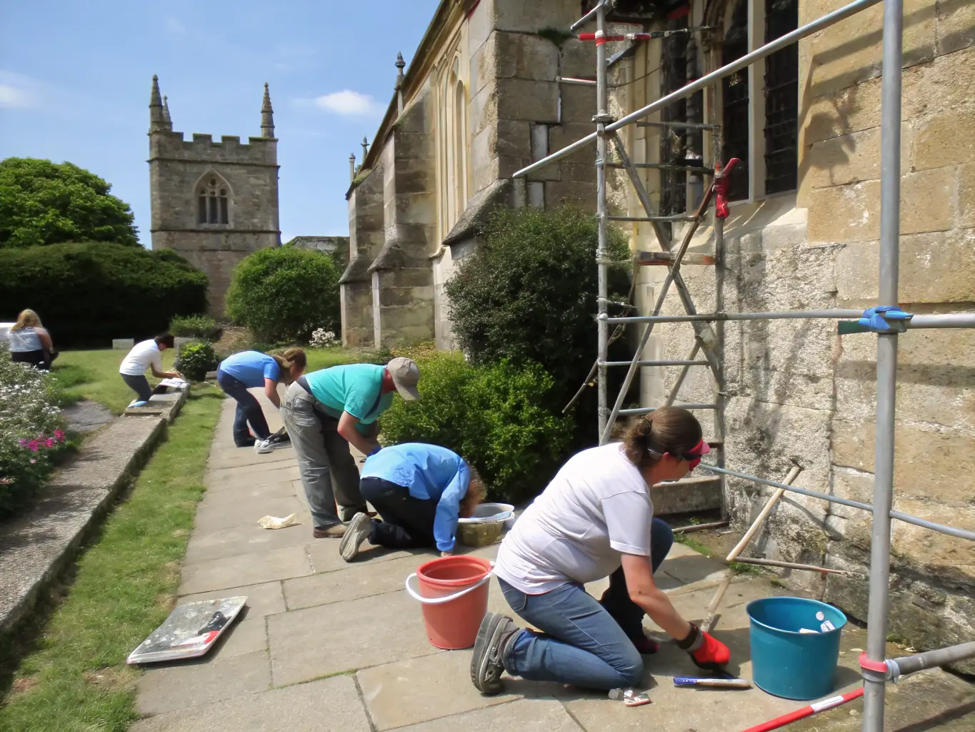 A photograph depicting a group of volunteers restoring the exterior of a historic writer's house, showcasing the organization's commitment to preserving literary landmarks.